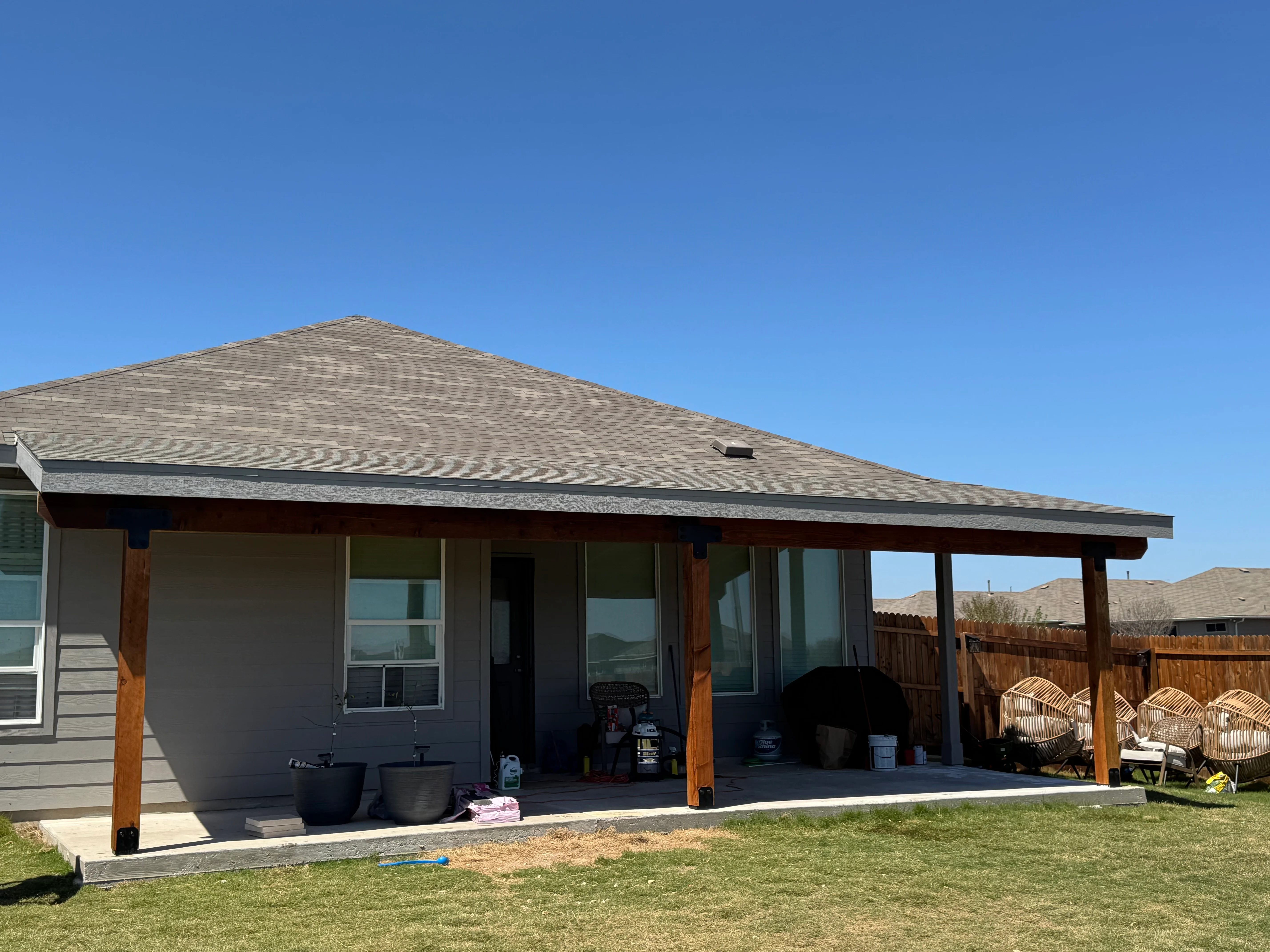 Covered patio with gabled roof, wood posts, concrete pad, and open-air design