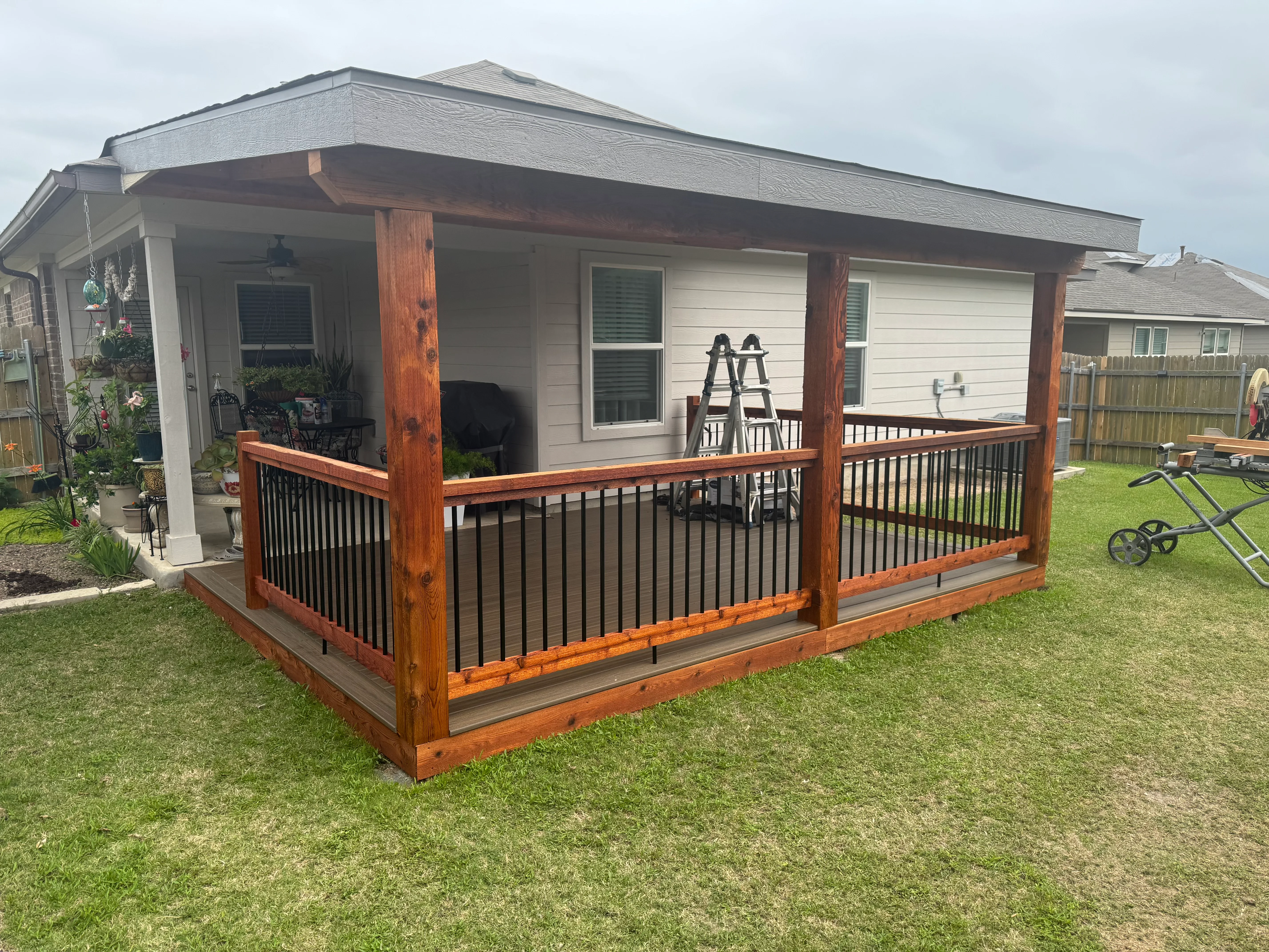 Cedar deck with black metal railings and covered roof structure attached to home