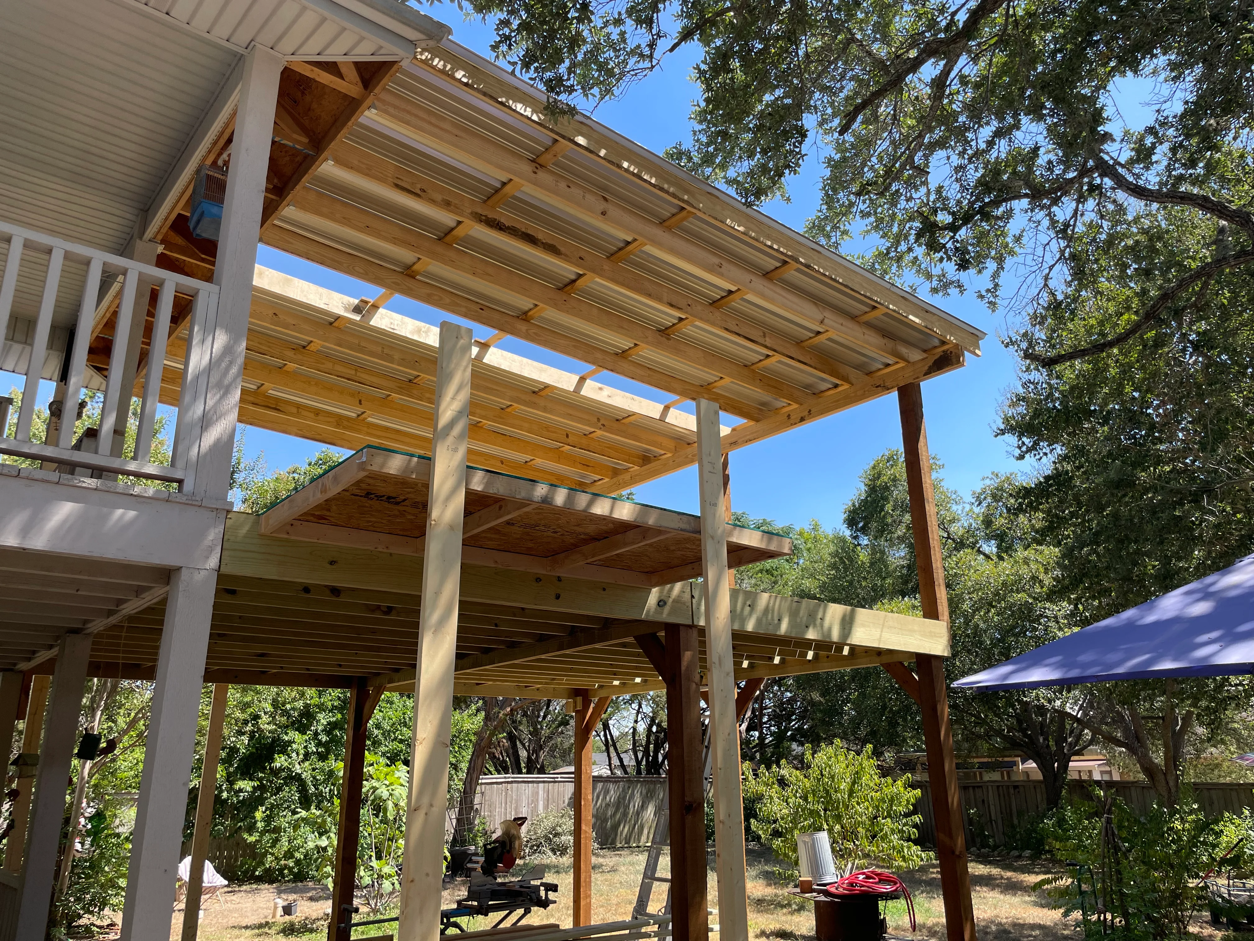Multi-level wood pergola with shade panels, timber posts, and horizontal slat roof structure