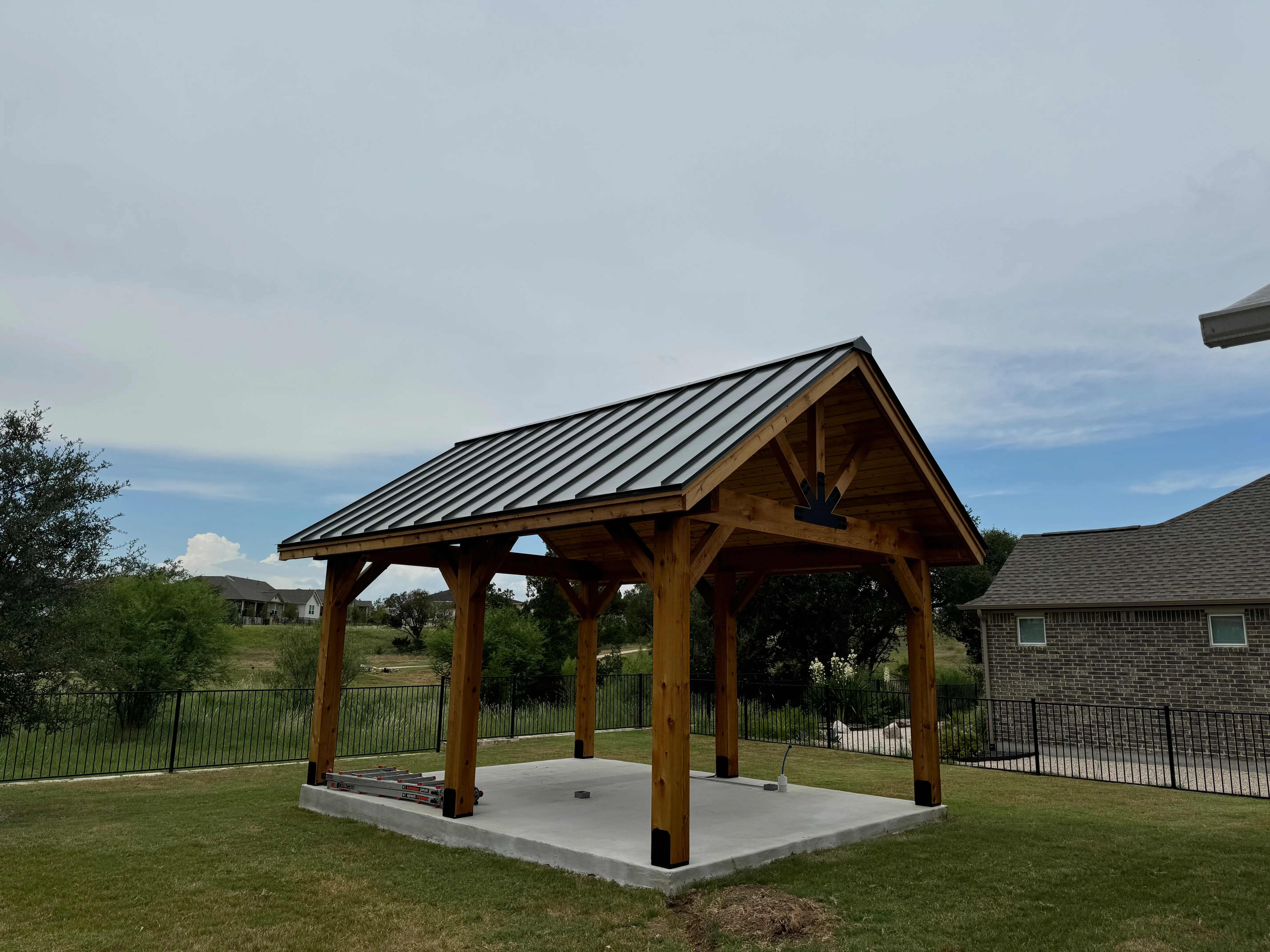 Timber frame pavilion with standing seam metal roof and concrete pad foundation