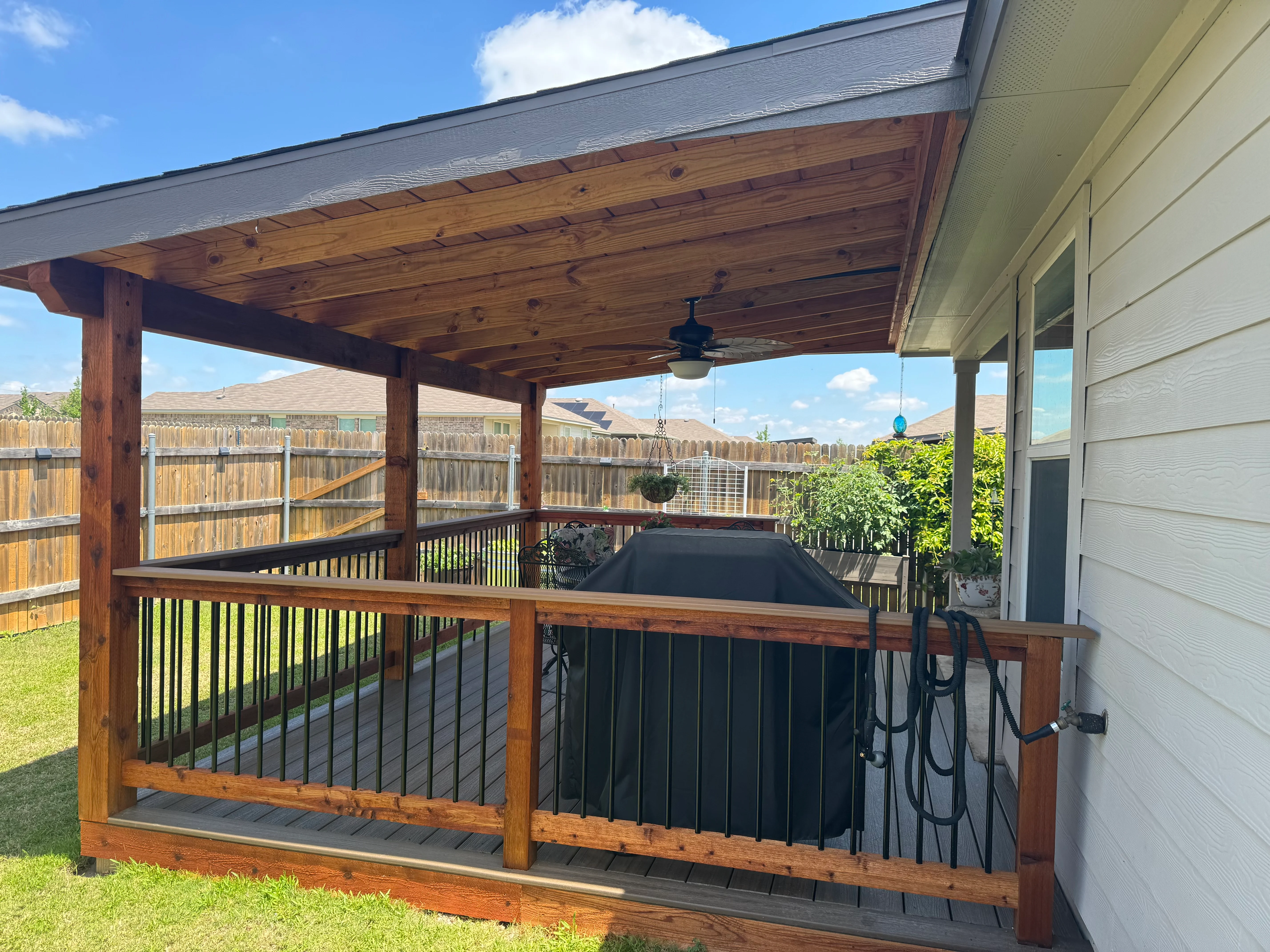 Covered deck with wood beams, metal spindle railing, and composite decking