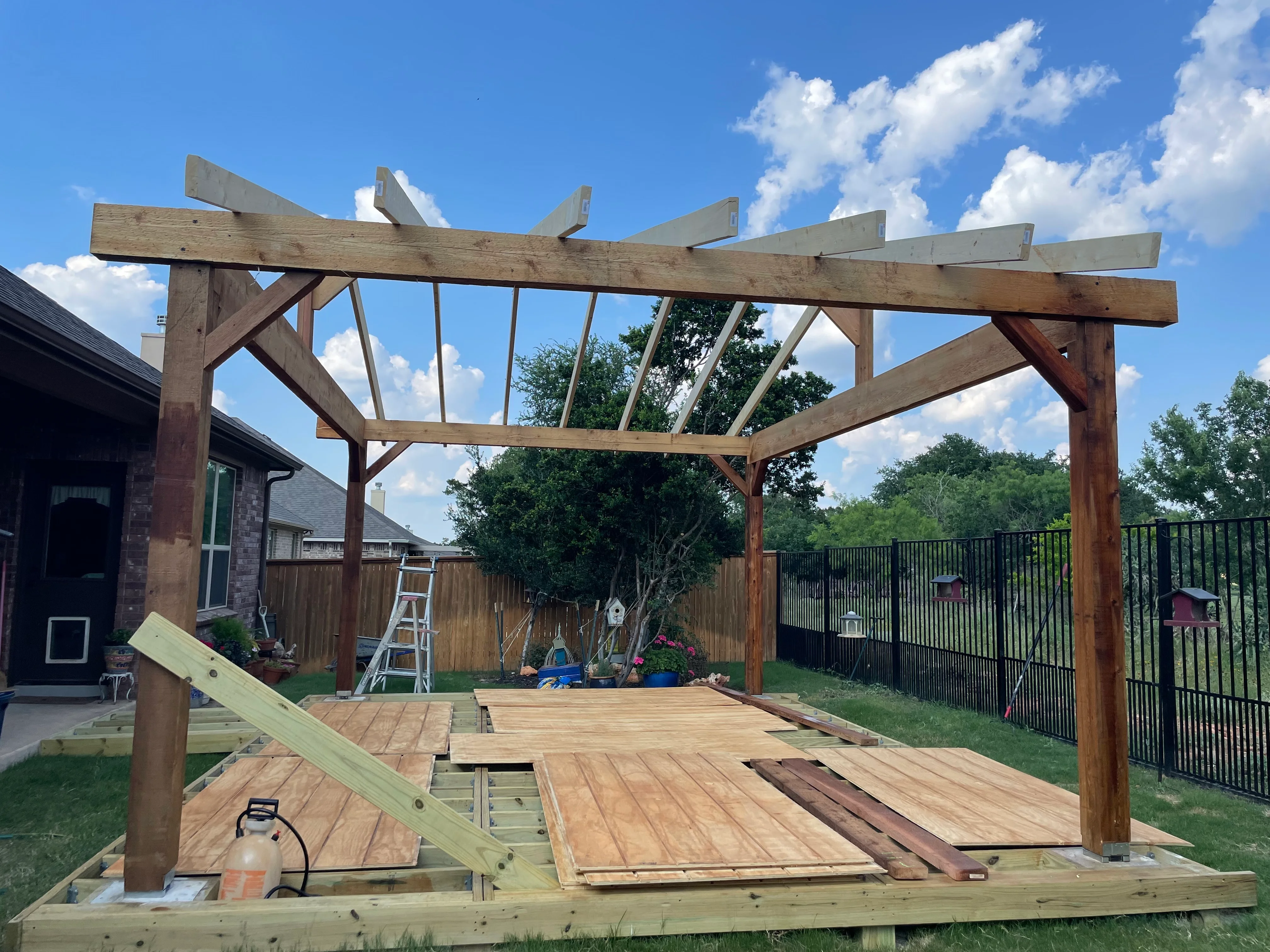 Timber pergola with angled roof slats over composite deck with wooden posts and metal brackets