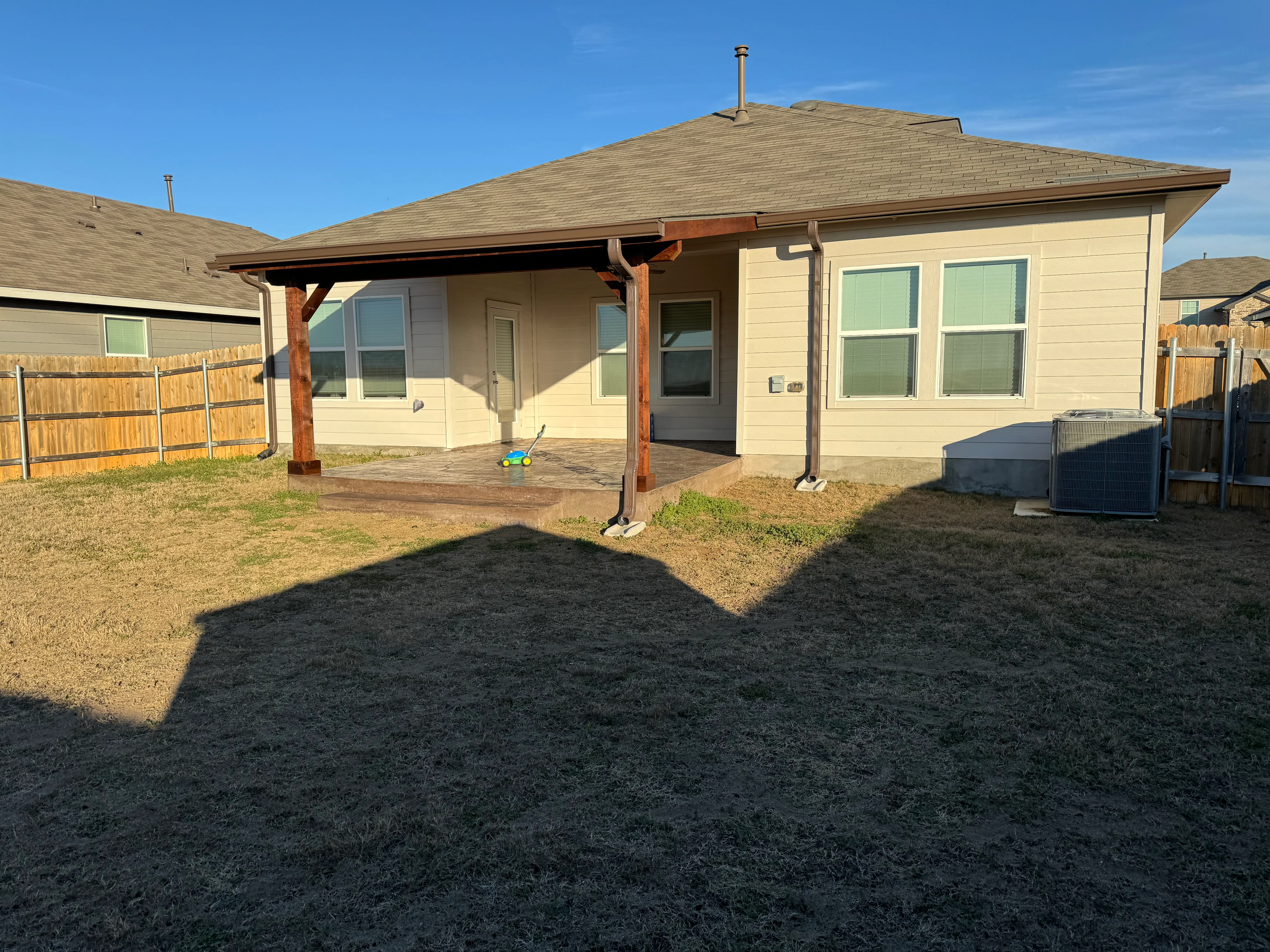Covered patio with wood posts, beams, and composite deck attached to residential home