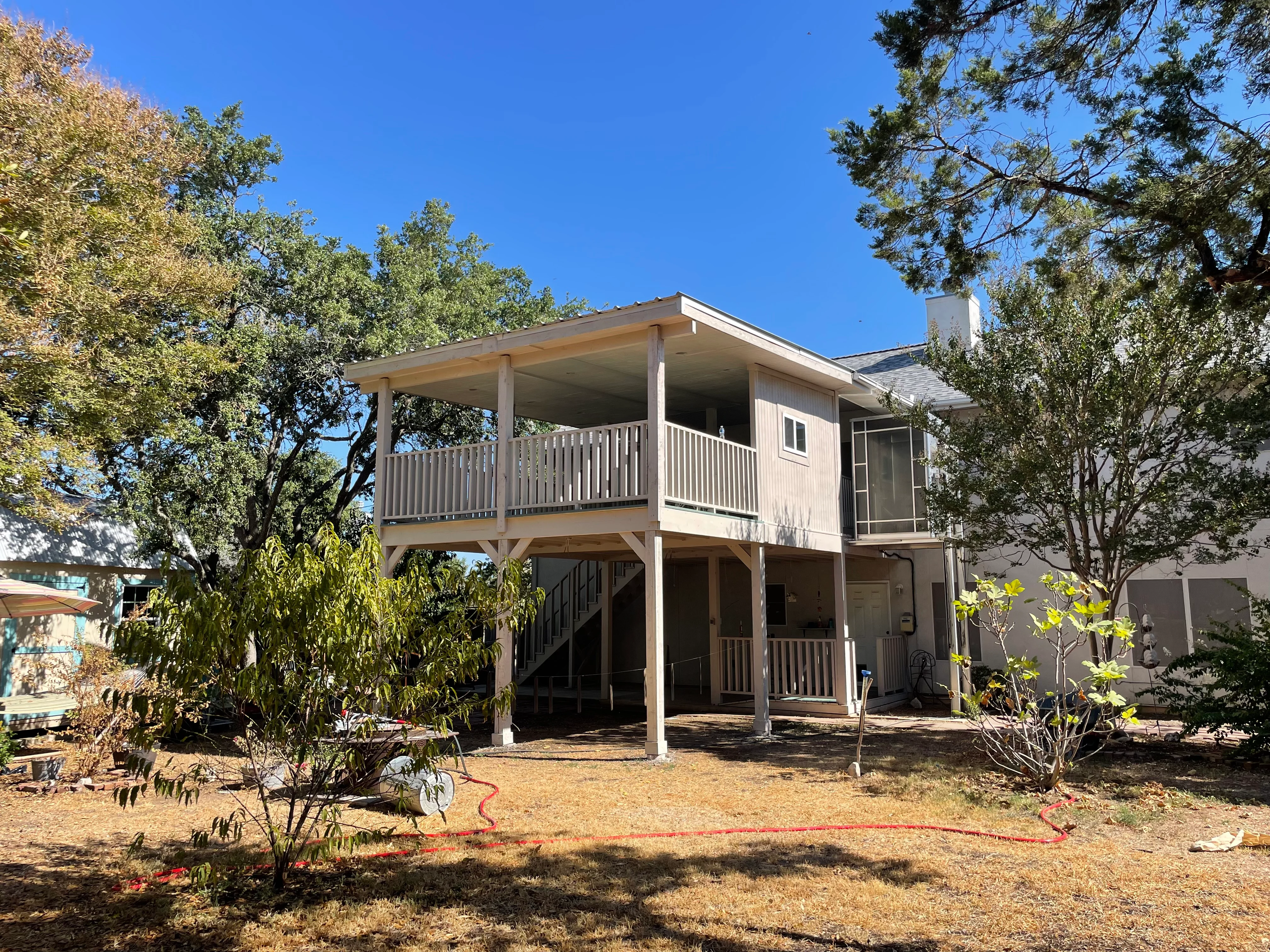 Elevated deck with white railings, covered patio, and pressure-treated lumber framing