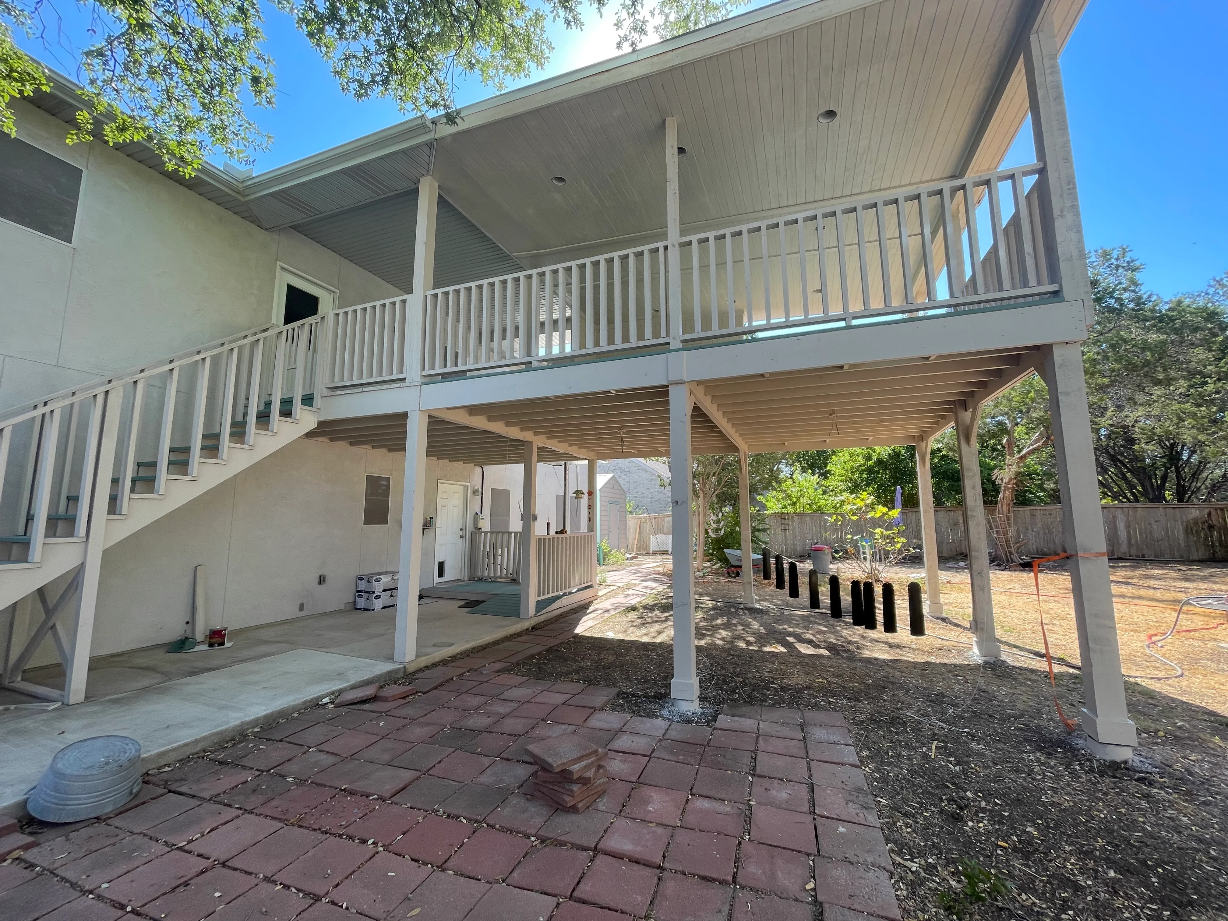 Two-story white vinyl deck with covered patio, composite pavers, and metal railings
