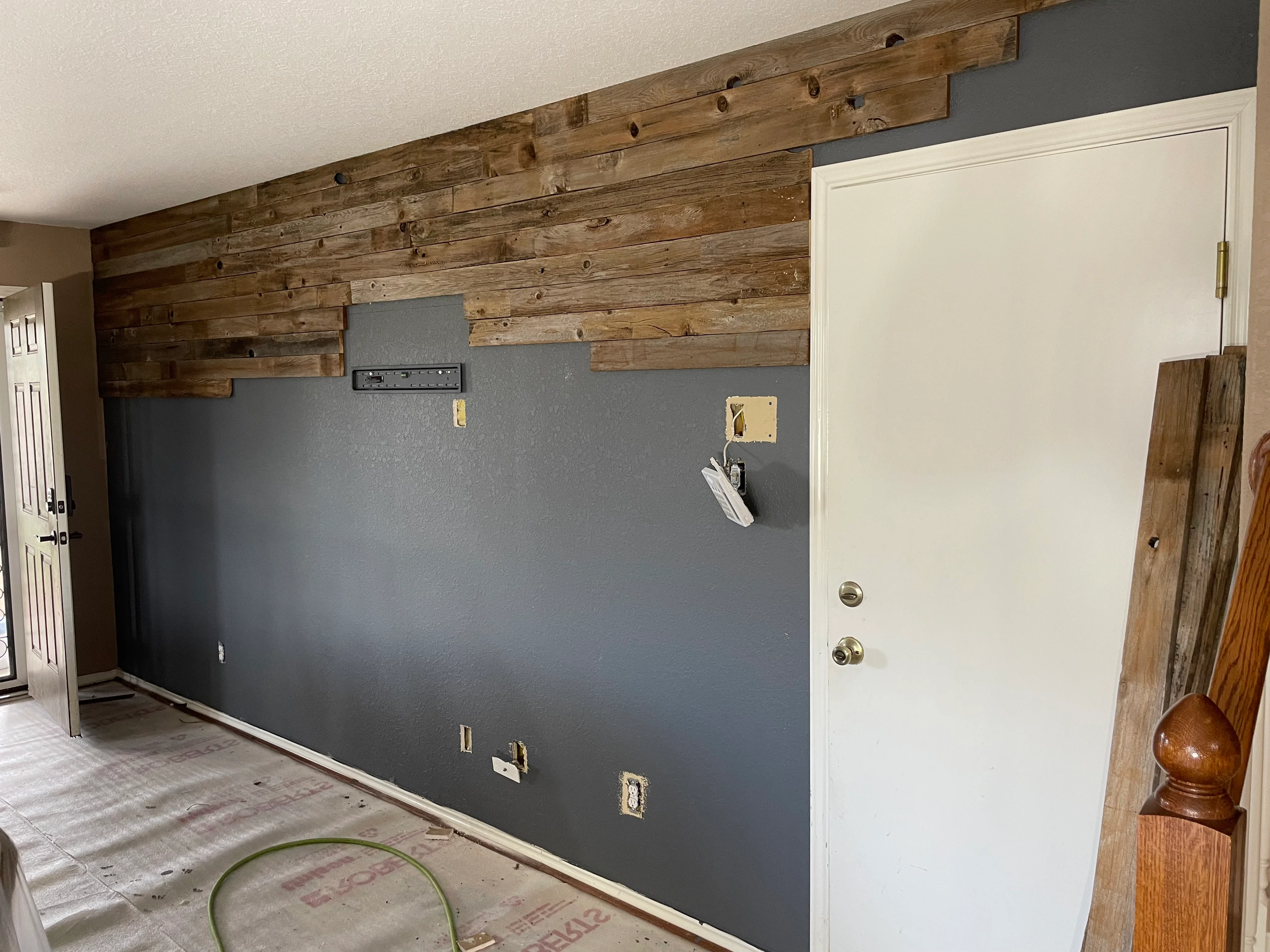 Reclaimed wood plank accent wall above gray drywall with integrated electrical outlets