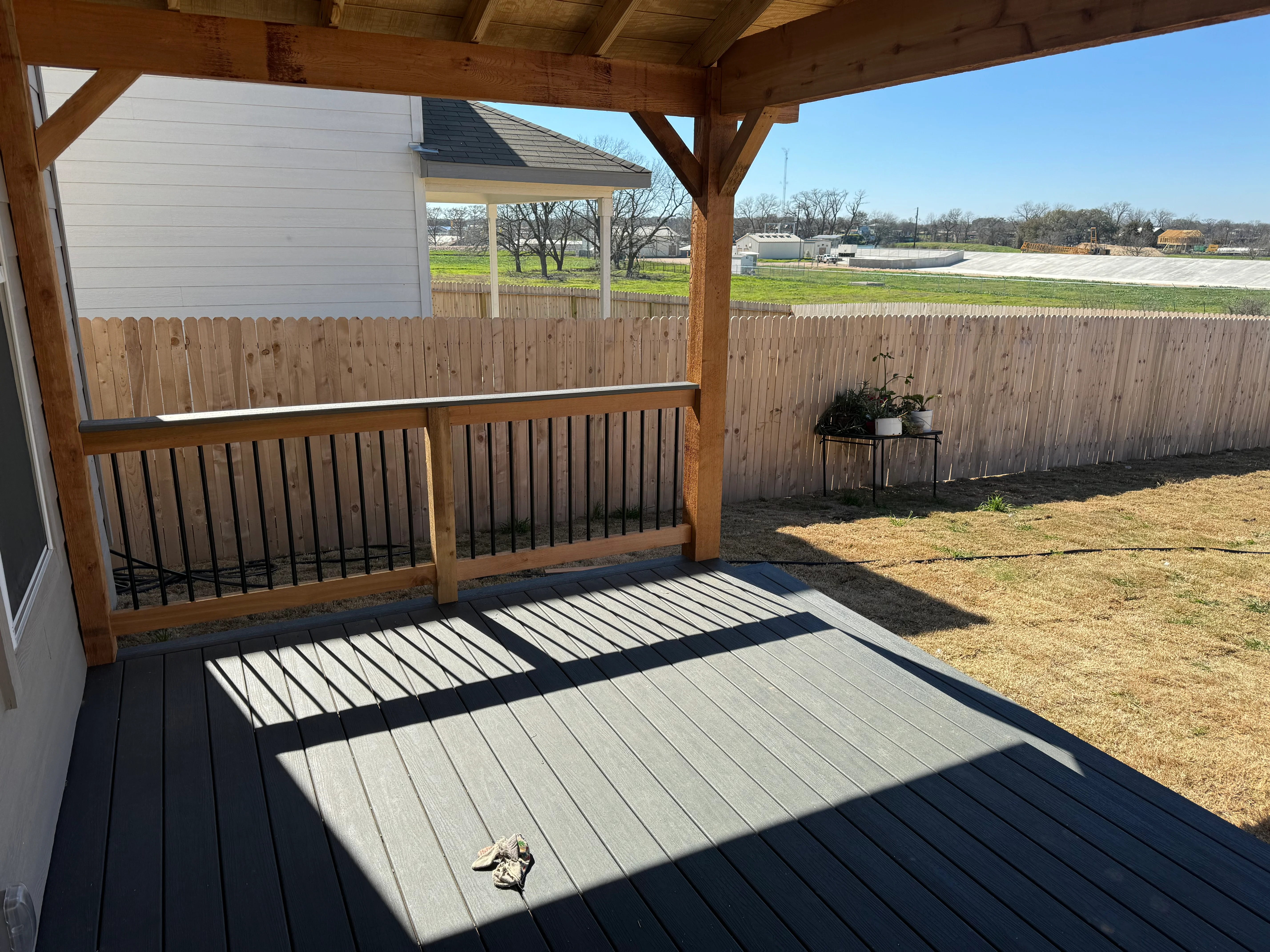 Covered deck with timber pergola, composite decking, and metal railings overlooking rural landscape