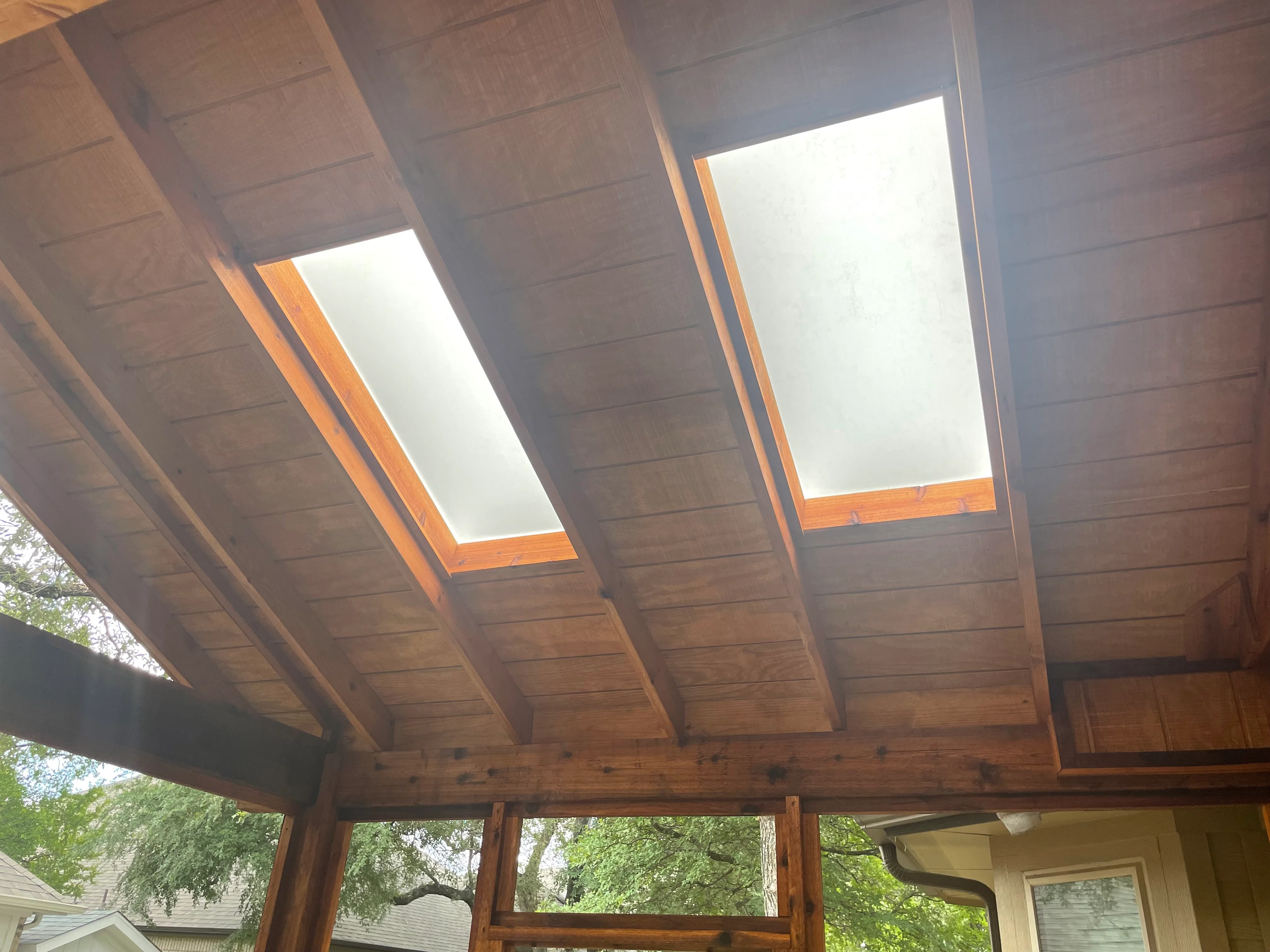 Wood patio cover with exposed beams and two skylights, natural wood framing