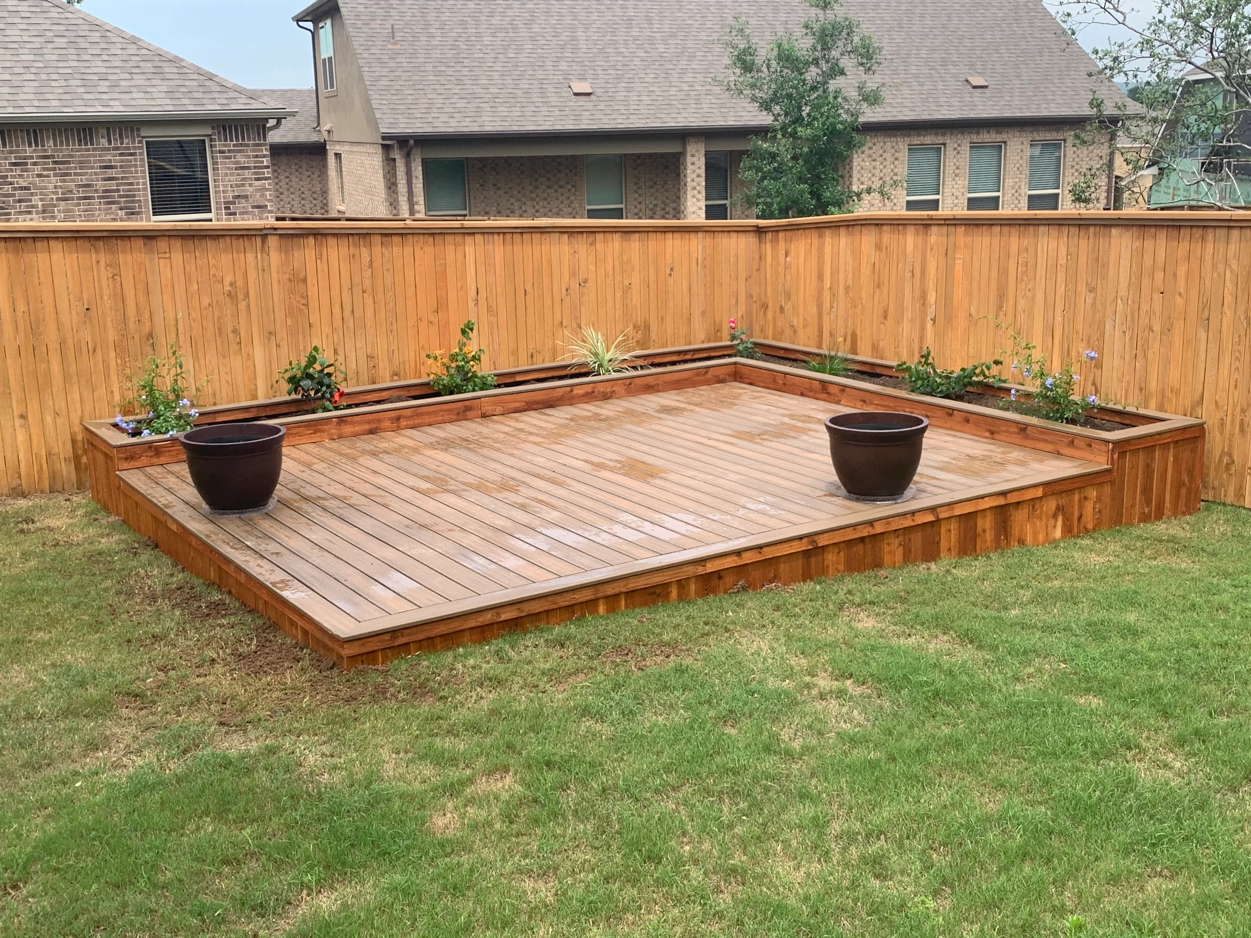 Composite deck with integrated wood planter boxes, bench seating, and cedar fence