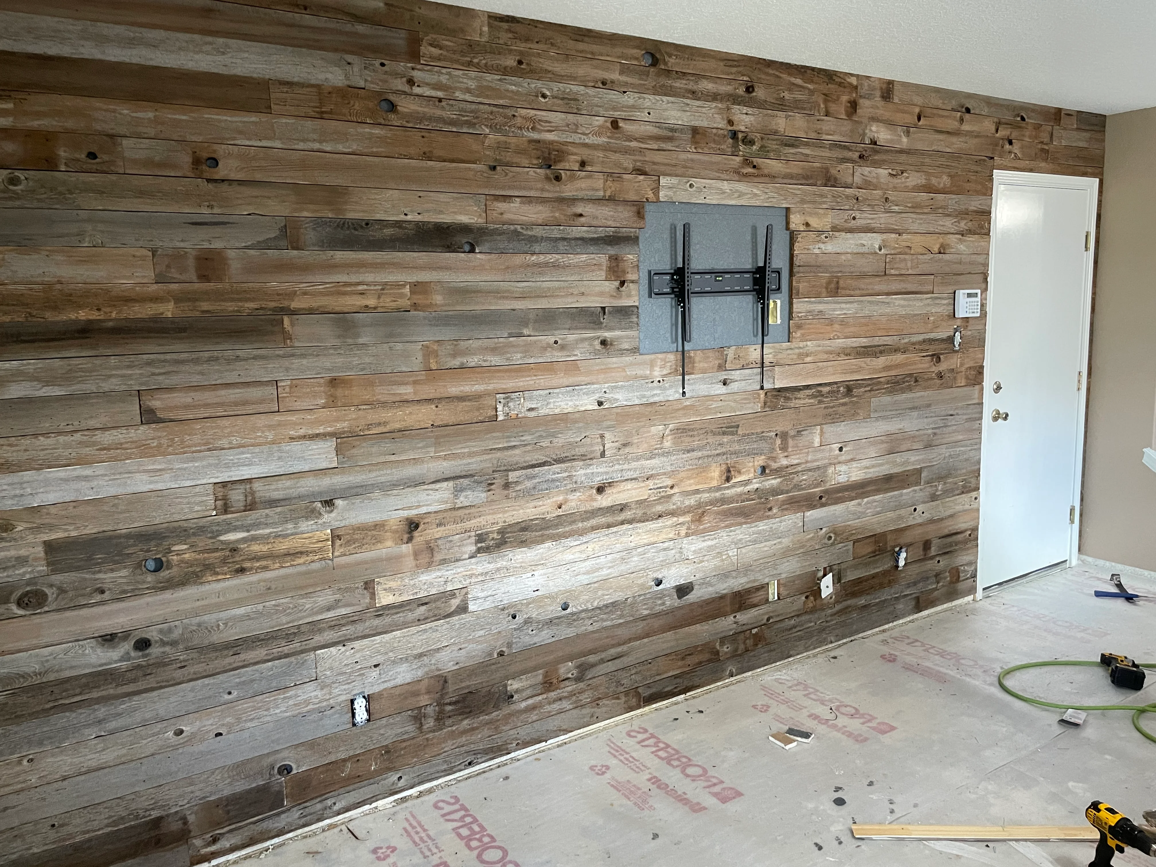 Reclaimed wood accent wall with horizontal planks, mixed tones, and integrated TV mount bracket